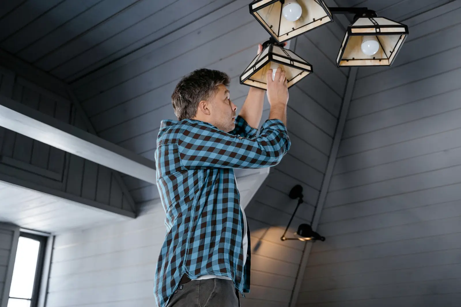 Électricien posant un luminaire au plafond