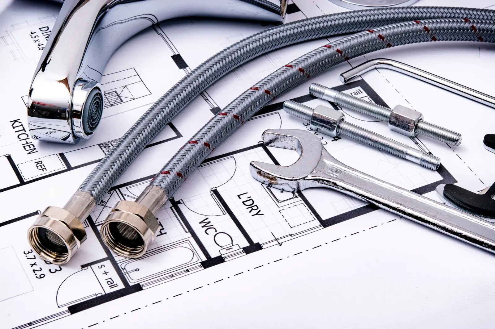 Flexibles de plomberie et clé sur un plan d'installation