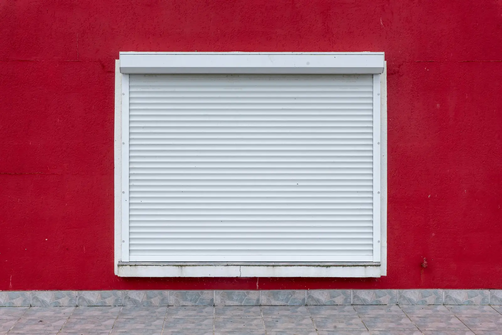 Volet roulant blanc sur un mur rouge